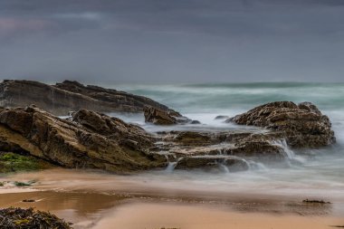 Avustralya, NSW 'nin güney kıyısındaki Eurobadalla Shire' de Bermagui 'de bulutlu ve dalgalı gün doğumu deniz manzarası..