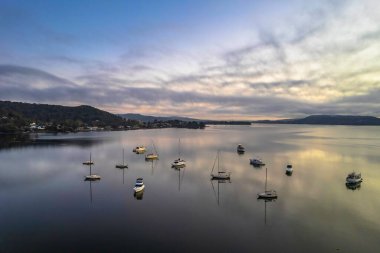 Central Coast, NSW, Avustralya 'daki Koolewong rıhtımında tekneler ve yansımalarla yumuşak bir hava gündoğumu..