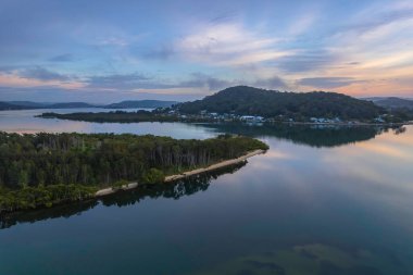 Gündoğumu, bulutlar ve yansımalar Orta Sahildeki Woy Woy Rıhtımı 'nda, NSW, Avustralya.