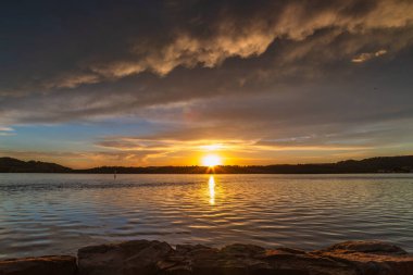 Güneş doğarken gökyüzü bulutlarla doludur. Woy Woy 'da merkez kıyısı, NSW, Avustralya..
