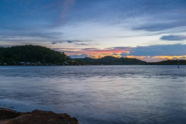 Güneş doğarken gökyüzü bulutlarla doludur. Woy Woy 'da merkez kıyısı, NSW, Avustralya..