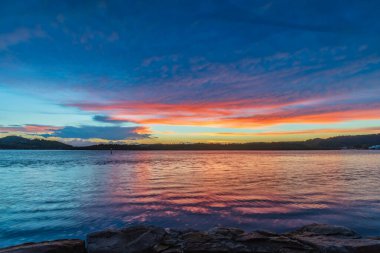 Güneş doğarken gökyüzü bulutlarla doludur. Woy Woy 'da merkez kıyısı, NSW, Avustralya..