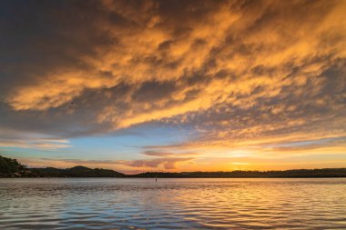 Güneş doğarken gökyüzü bulutlarla doludur. Woy Woy 'da merkez kıyısı, NSW, Avustralya..