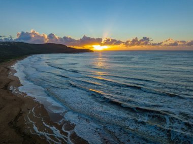 Central Coast, NSW, Avustralya 'daki Killcare Sahili' nde deniz köpüğü ve bulut kütleli gün doğumu denizi..