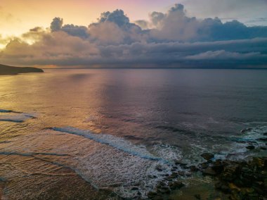 Central Coast, NSW, Avustralya 'daki Killcare Sahili' nde yağmur bulutlarıyla birlikte gün doğumu denizi..