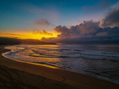 Central Coast, NSW, Avustralya 'daki Killcare Sahili' nde yağmur bulutlarıyla birlikte gün doğumu denizi..