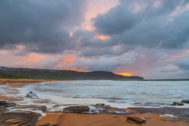 Deniz kenarında gün doğumu bulutlarla ve gökyüzünde pembe bir dokunuşla Central Coast, NSW, Avustralya 'daki Killcare Plajı' nda..