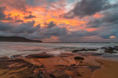 Deniz kenarında gün doğumu bulutlarla ve gökyüzünde pembe bir dokunuşla Central Coast, NSW, Avustralya 'daki Killcare Plajı' nda..