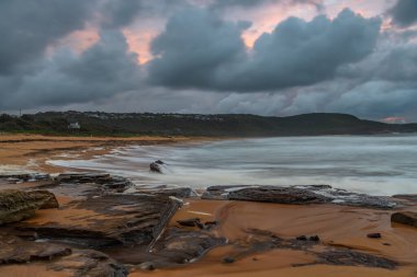 Deniz kenarında gün doğumu bulutlarla ve gökyüzünde pembe bir dokunuşla Central Coast, NSW, Avustralya 'daki Killcare Plajı' nda..