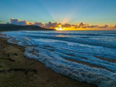 Deniz köpüğü, güneş ışığı ve bulut kütleli gündoğumu deniz manzarası Central Coast, NSW, Avustralya 'daki Killcare Sahili' nde..