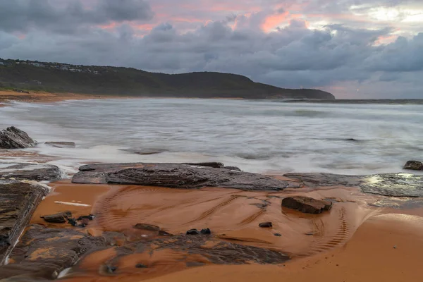 Deniz kenarında gün doğumu bulutlarla ve gökyüzünde pembe bir dokunuşla Central Coast, NSW, Avustralya 'daki Killcare Plajı' nda..