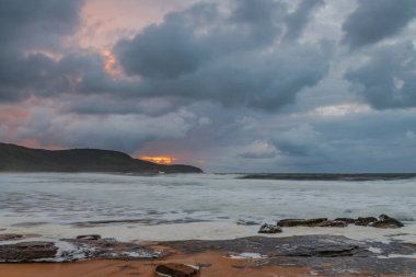 Deniz kenarında gün doğumu bulutlarla ve gökyüzünde pembe bir dokunuşla Central Coast, NSW, Avustralya 'daki Killcare Plajı' nda..