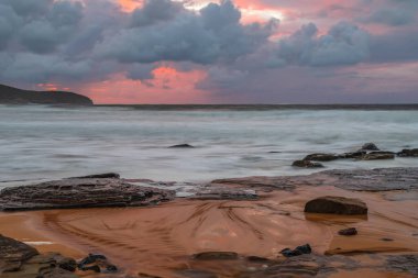 Deniz kenarında gün doğumu bulutlarla ve gökyüzünde pembe bir dokunuşla Central Coast, NSW, Avustralya 'daki Killcare Plajı' nda..