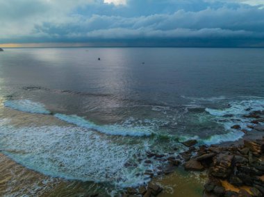 Central Coast, NSW, Avustralya 'daki Killcare Sahili' nde yağmur bulutlarıyla birlikte gün doğumu denizi..