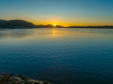 Nehir kıyısında hava güneşinin doğuşu. Woy Woy 'da bulutsuz bir gökyüzü. Merkez Sahili, NSW, Avustralya..