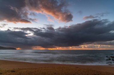 Deniz kıyısında gün doğumu, Killcare Sahili 'nde yağmur bulutları, NSW, Avustralya.