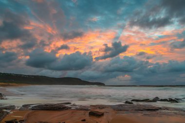 Deniz kenarında gün doğumu bulutlarla ve gökyüzünde pembe bir dokunuşla Central Coast, NSW, Avustralya 'daki Killcare Plajı' nda..
