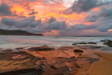 Deniz kenarında gün doğumu bulutlarla ve gökyüzünde pembe bir dokunuşla Central Coast, NSW, Avustralya 'daki Killcare Plajı' nda..