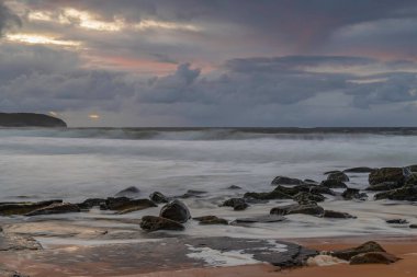 Deniz kenarında gün doğumu bulutlarla ve gökyüzünde pembe bir dokunuşla Central Coast, NSW, Avustralya 'daki Killcare Plajı' nda..