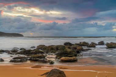 Deniz kenarında gün doğumu bulutlarla ve gökyüzünde pembe bir dokunuşla Central Coast, NSW, Avustralya 'daki Killcare Plajı' nda..