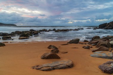 Deniz kenarında gün doğumu bulutlarla ve gökyüzünde pembe bir dokunuşla Central Coast, NSW, Avustralya 'daki Killcare Plajı' nda..
