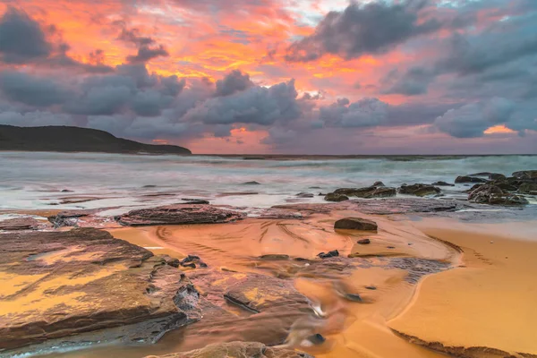 Sunrise at the seaside with clouds and touch of pink in the sky at Killcare Beach on the Central Coast, NSW, Australia.