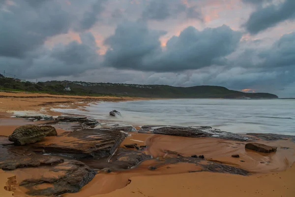 Sunrise at the seaside with clouds and touch of pink in the sky at Killcare Beach on the Central Coast, NSW, Australia.