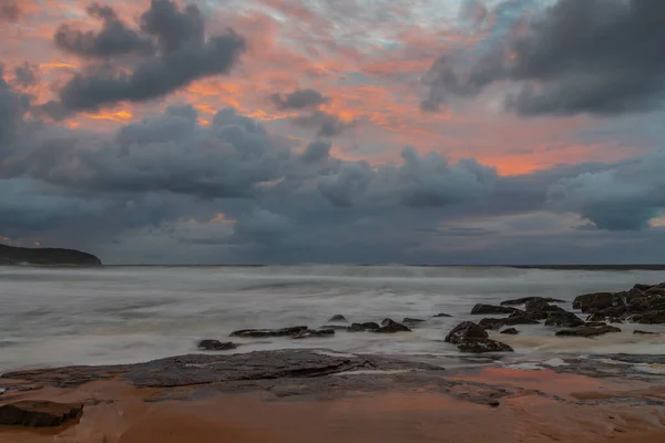 Sunrise at the seaside with clouds and touch of pink in the sky at Killcare Beach on the Central Coast, NSW, Australia.