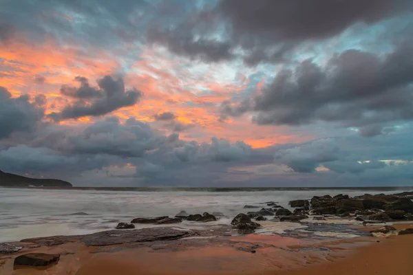 Sunrise at the seaside with clouds and touch of pink in the sky at Killcare Beach on the Central Coast, NSW, Australia.