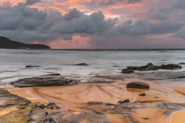 Sunrise at the seaside with clouds and touch of pink in the sky at Killcare Beach on the Central Coast, NSW, Australia.