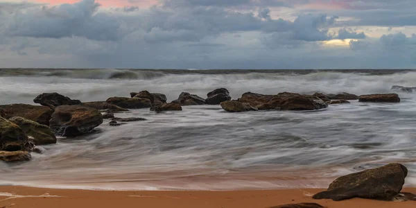 Sunrise at the seaside with clouds and touch of pink in the sky at Killcare Beach on the Central Coast, NSW, Australia.