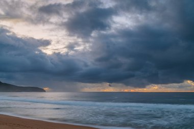 Deniz kıyısında gün doğumu, Killcare Sahili 'nde yağmur bulutları, NSW, Avustralya.