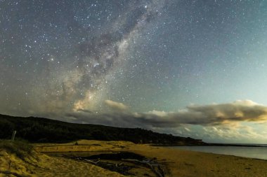 Gecenin karanlığında, Samanyolu 'nun altındaki sahilde ve Avustralya, NSW' nin merkez kıyısındaki Putty Beach 'te yıldızlar..