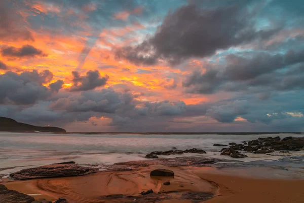 Sunrise at the seaside with clouds and touch of pink in the sky at Killcare Beach on the Central Coast, NSW, Australia.