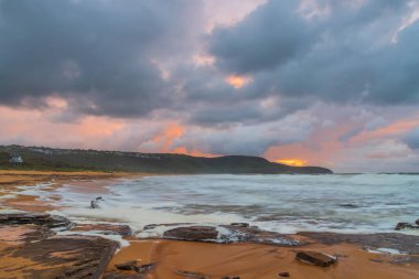 Deniz kenarında gün doğumu bulutlarla ve gökyüzünde pembe bir dokunuşla Central Coast, NSW, Avustralya 'daki Killcare Plajı' nda..