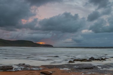 Deniz kenarında gün doğumu bulutlarla ve gökyüzünde pembe bir dokunuşla Central Coast, NSW, Avustralya 'daki Killcare Plajı' nda..