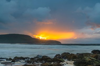 Deniz kenarında gün doğumu bulutlarla ve gökyüzünde pembe bir dokunuşla Central Coast, NSW, Avustralya 'daki Killcare Plajı' nda..