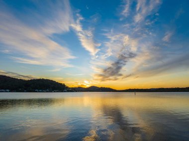 Orta Sahildeki Woy Woy, NSW, Avustralya 'da yüksek bulutlu ve yumuşak pastel renklere sahip hava gündoğumu su manzarası..