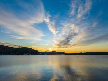 Orta Sahildeki Woy Woy, NSW, Avustralya 'da yüksek bulutlu ve yumuşak pastel renklere sahip hava gündoğumu su manzarası..