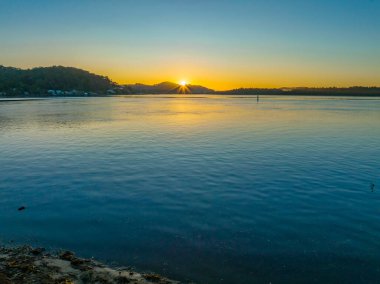 Nehir kıyısında hava güneşinin doğuşu. Woy Woy 'da bulutsuz bir gökyüzü. Merkez Sahili, NSW, Avustralya..