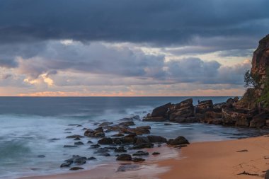 Deniz kıyısında gün doğumu, Killcare Sahili 'nde yağmur bulutları, NSW, Avustralya.