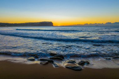 Sahil kenarında açık gökyüzü ve Avustralya 'nın NSW bölgesindeki MacMasters Sahili' nde alçak bulut kütleli hava gündoğumu..