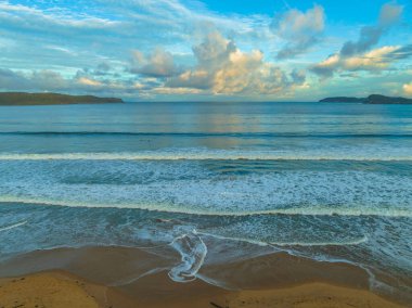 Central Coast, NSW, Avustralya 'daki Umina Sahili' nde küçük dalgalar ve yağmur bulutlarıyla gün batımı deniz manzarası..