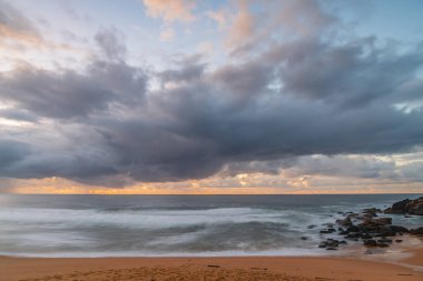 Deniz kıyısında gün doğumu, Killcare Sahili 'nde yağmur bulutları, NSW, Avustralya.