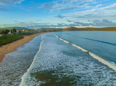 Central Coast, NSW, Avustralya 'daki Umina Sahili' nde küçük dalgalar ve yağmur bulutlarıyla gün batımı deniz manzarası..
