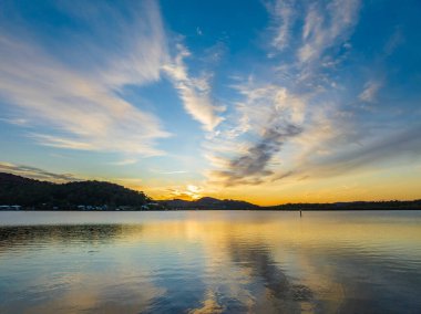 Orta Sahildeki Woy Woy, NSW, Avustralya 'da yüksek bulutlu ve yumuşak pastel renklere sahip hava gündoğumu su manzarası..