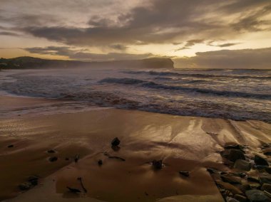 Orta Sahildeki MacMasters Sahili 'nde, NSW, Avustralya' da 2,5 ila 4,5 metrelik dalgalar ve yağmur bulutlarıyla havadan gün doğumu..