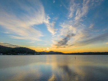 Orta Sahildeki Woy Woy, NSW, Avustralya 'da yüksek bulutlu ve yumuşak pastel renklere sahip hava gündoğumu su manzarası..