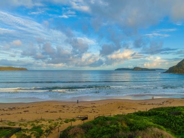 Central Coast, NSW, Avustralya 'daki Umina Sahili' nde küçük dalgalar ve yağmur bulutlarıyla gün batımı deniz manzarası..