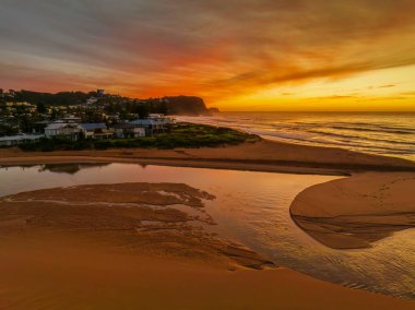 Avoca Lagoon ve Avoca Sahili 'ndeki NSW, Avustralya' daki Avoca Sahili 'nde bulutlu ve yumuşak denizli hava gündoğumu.